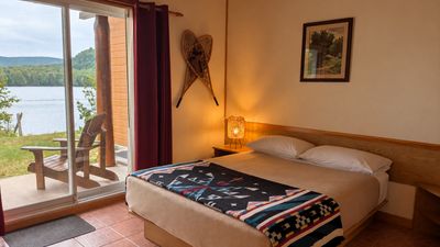Chambre avec lit, porte-patio ouverte et vue directe sur le lac Saguay