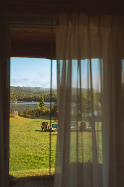 Vue depuis une chambre sur le lac Saguay, les chaises Adirondack et les collines boisées